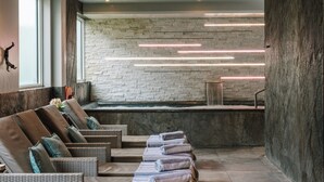 Un espace spa doté d’un mur en pierre, d’un bain à remous et de sièges avec des serviettes à disposition.
