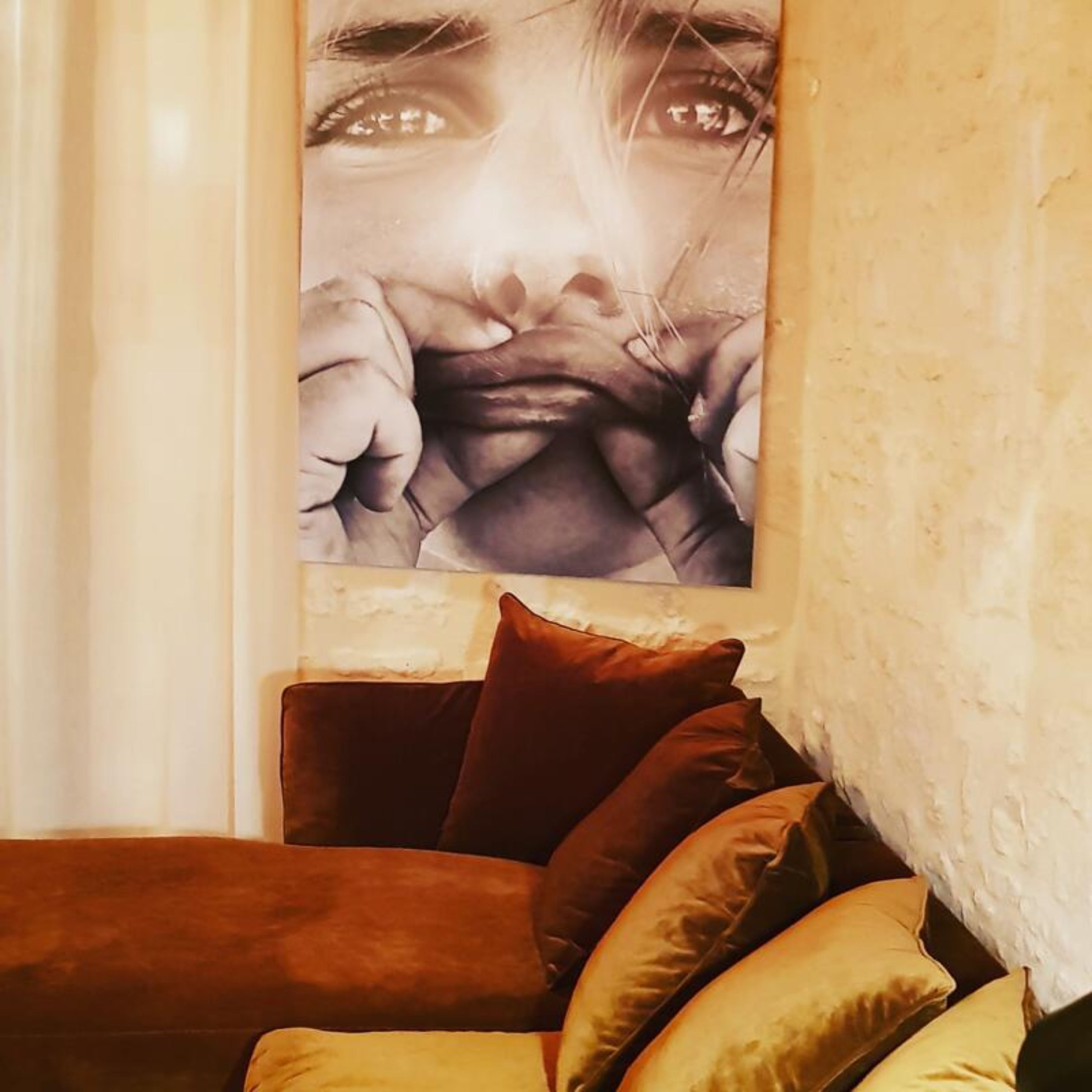 Ein Zimmer mit einem braunen Sofa und einem großen, abstrakten Gemälde an der Wand.