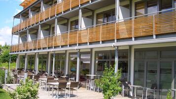 Ein modernes Gebäude mit einer Holzdachterrasse und einer Sitzgelegenheit im Freien.