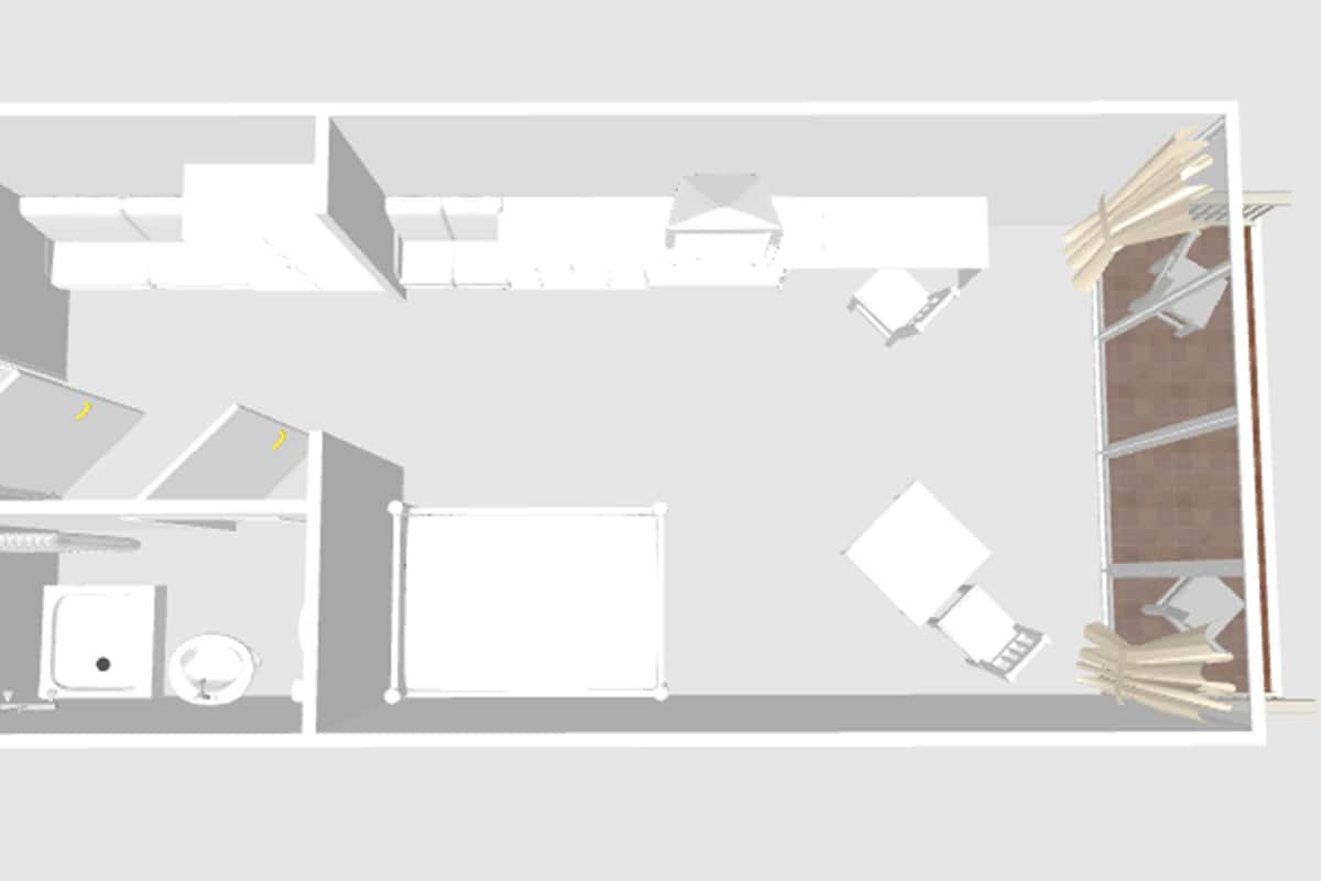 A floor plan of a hotel room with a bed, a desk, a chair, a wardrobe, and a bathroom.