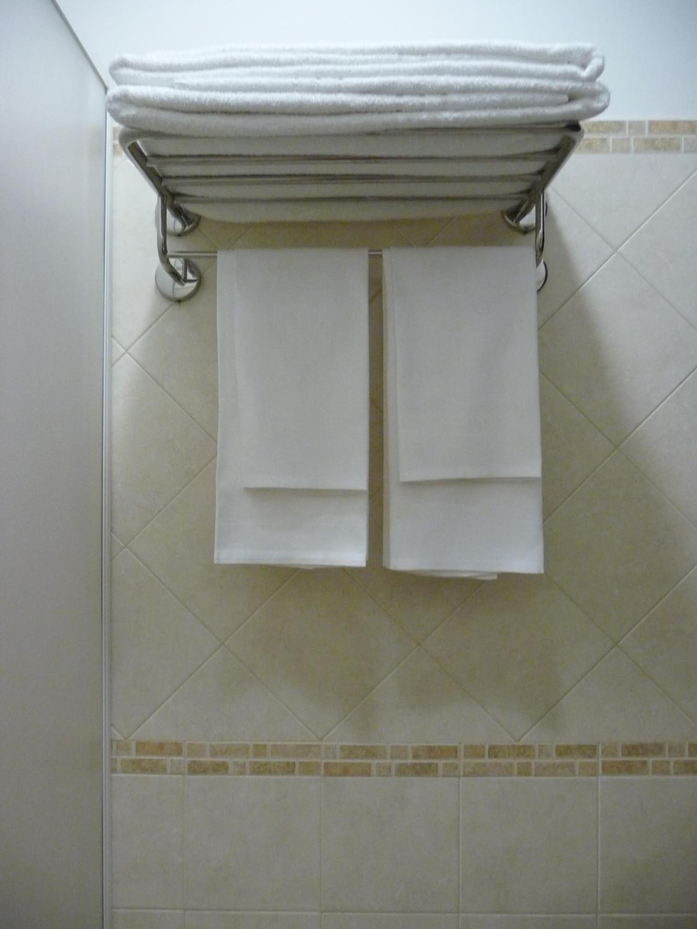 A bathroom with a towel rack holding two folded towels.