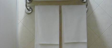 A bathroom with a towel rack holding two folded towels.