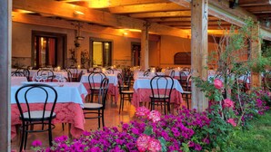 An outdoor dining area with tables and chairs, surrounded by flowers and plants. - Corte Aragonese (Santa Maria di Licodia)