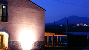 A modern building with a stone facade and a well-lit entrance. - Corte Aragonese (Santa Maria di Licodia)