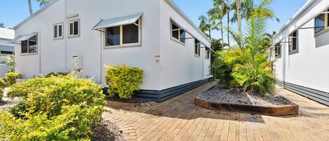 A modern building with a flat roof, rectangular windows, and a paved walkway.