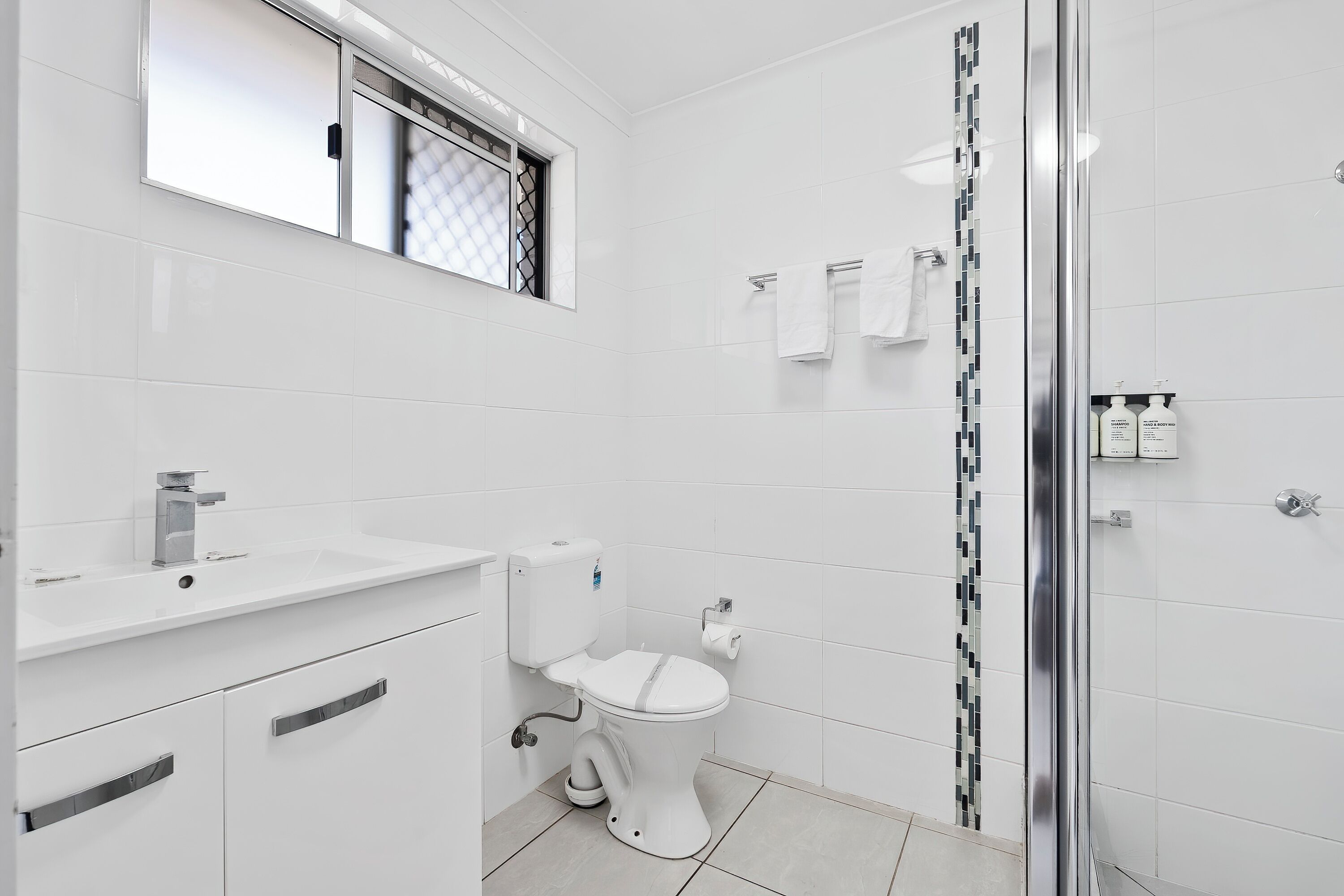 A modern bathroom with a toilet, sink, and shower.