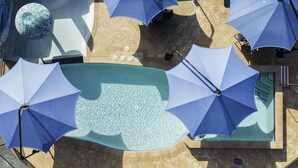 Área de piscina no terraço, com vários guarda-sóis e um objeto esférico decorativo.
