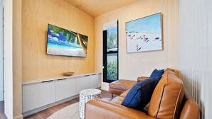 Uma sala de estar moderna com um sofá de couro, uma televisão de tela plana, uma parede de madeira e uma janela.