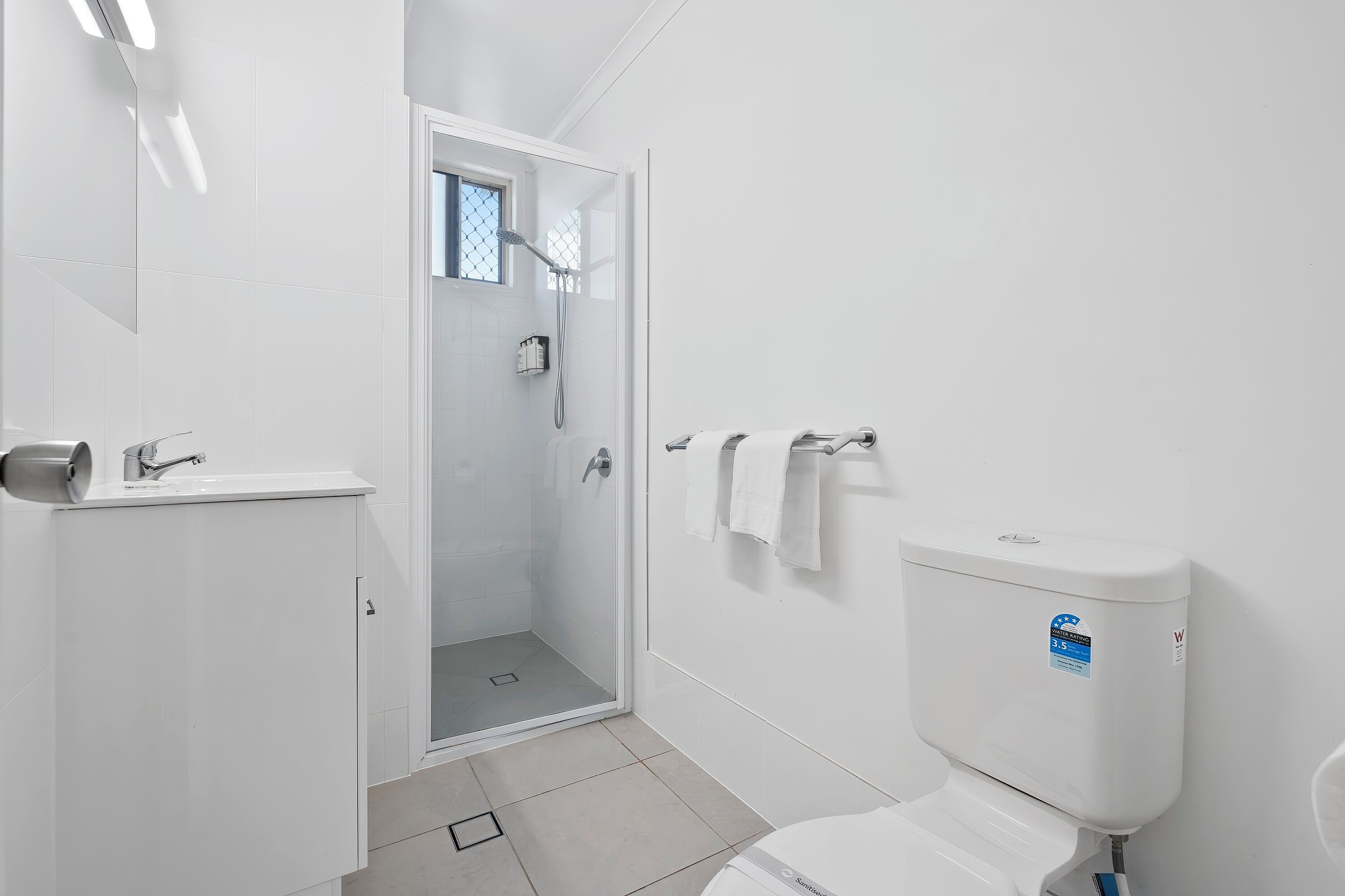 A bathroom with a toilet, a shower, and a sink.