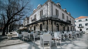 Ein historisches Gebäude mit einer überdachten Außenbestuhlung und mehreren Tischen und Stühlen.