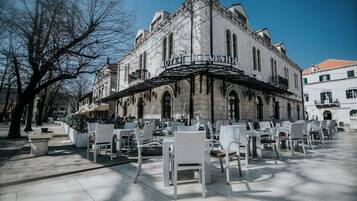 Ein historisches Gebäude mit einem Café-Bereich und Außenplätzen.