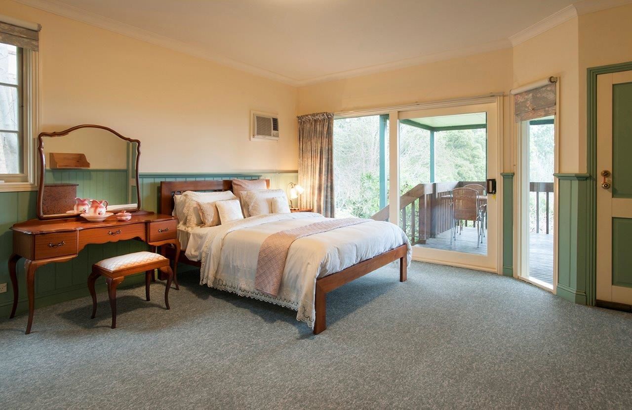 A bedroom with a bed, a desk, a chair, and a window.