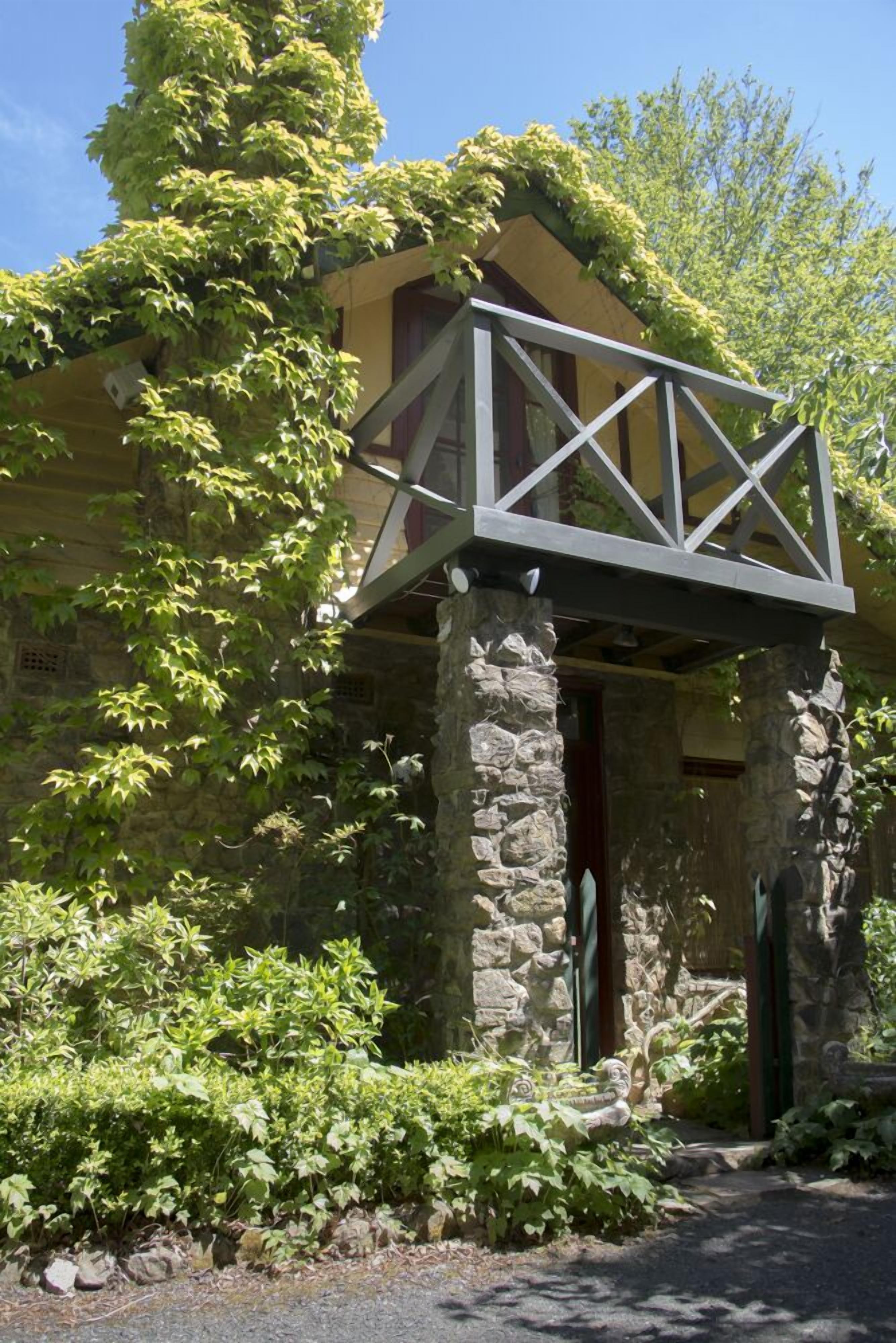 A stone building with a wooden porch supported by a metal framework.