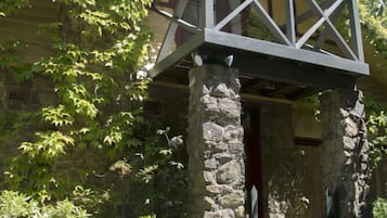 A stone building with a wooden porch supported by a metal framework.