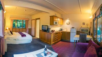 Una habitación de hotel con una cama, un escritorio, una kitchenette y un comedor.