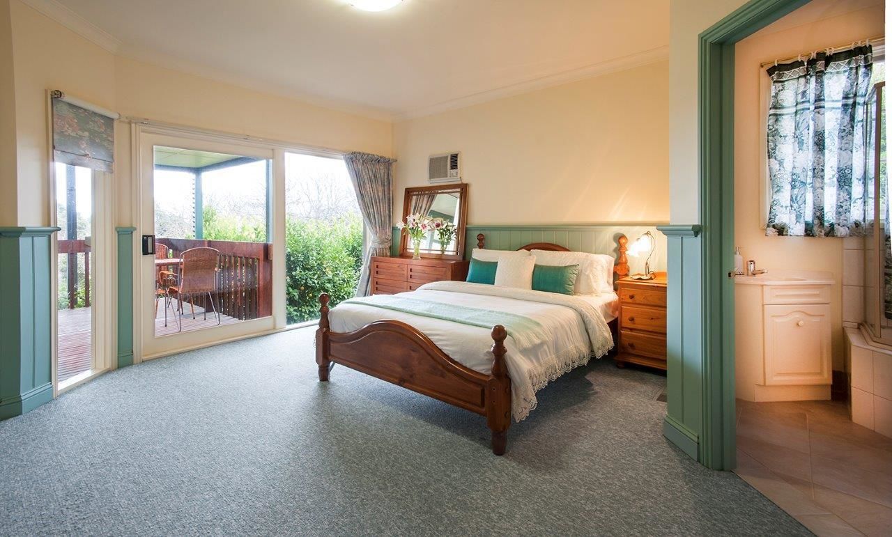 A bedroom with a wooden bed, a dresser, a mirror, and a window with curtains.