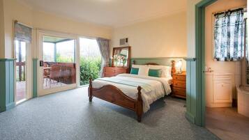 A bedroom with a wooden bed, a dresser, a mirror, and a window with curtains.