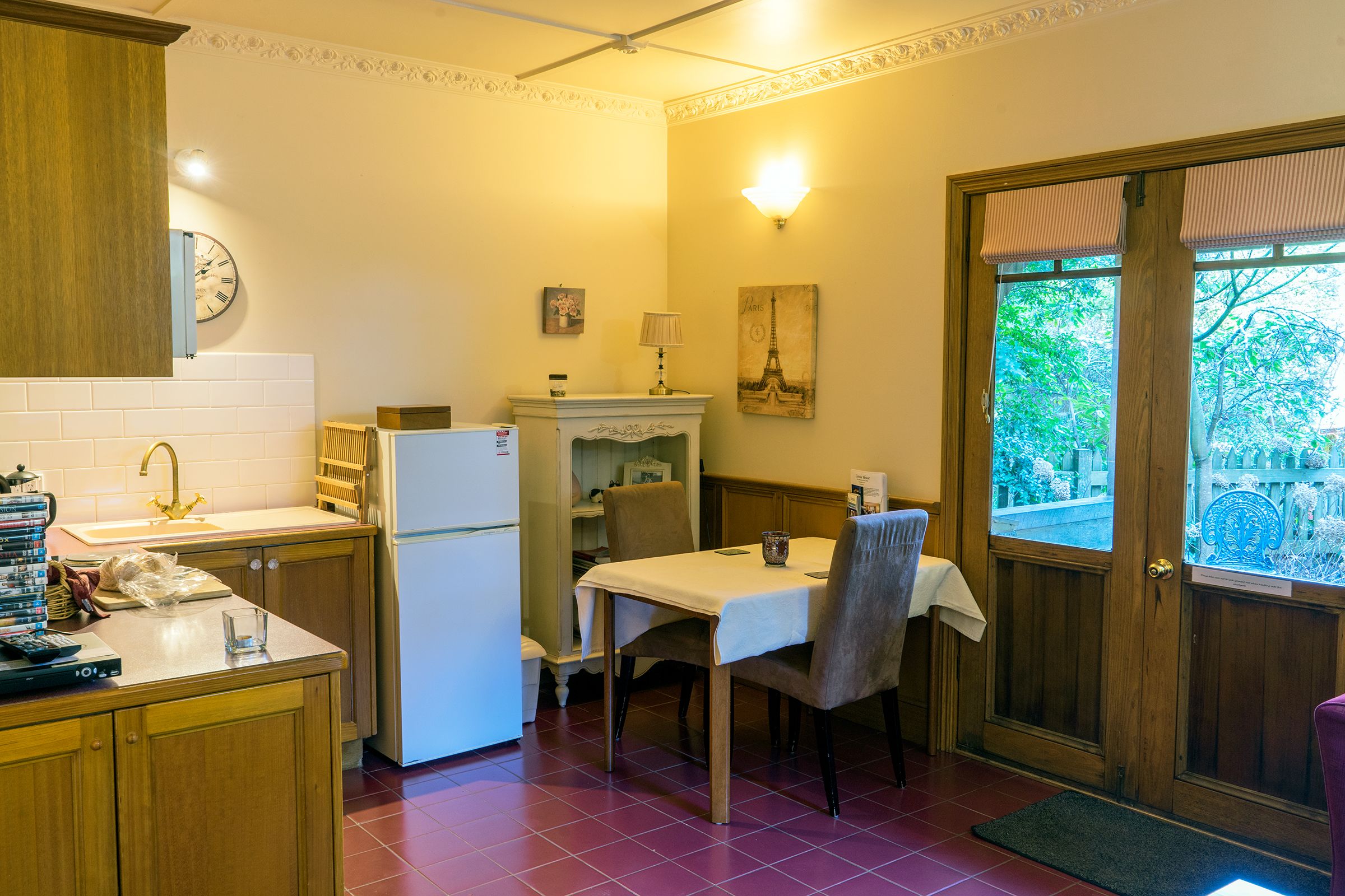 Una cocina compacta con refrigerador, lavamanos y mesa de comedor.