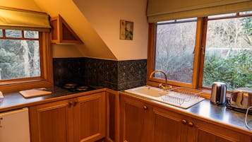 Una cocina con armarios de madera, un lavamanos, una ventana con vista a árboles y una estufa.