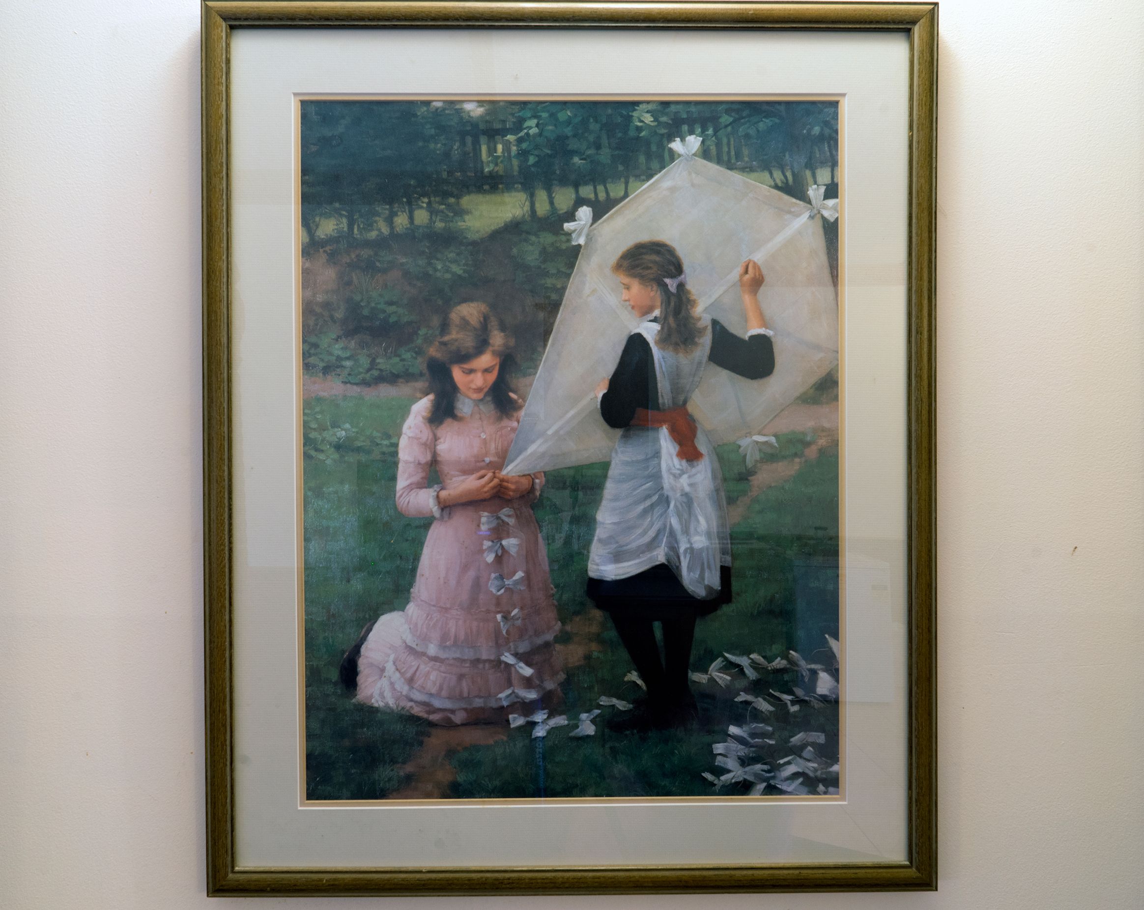 Un tableau encadré représentant deux femmes dans un jardin, l’une tenant un parasol.