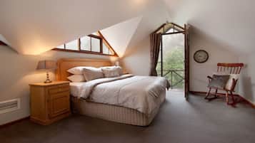Ein Schlafzimmer mit Bett, Nachttisch, Lampe und einem Schaukelstuhl.