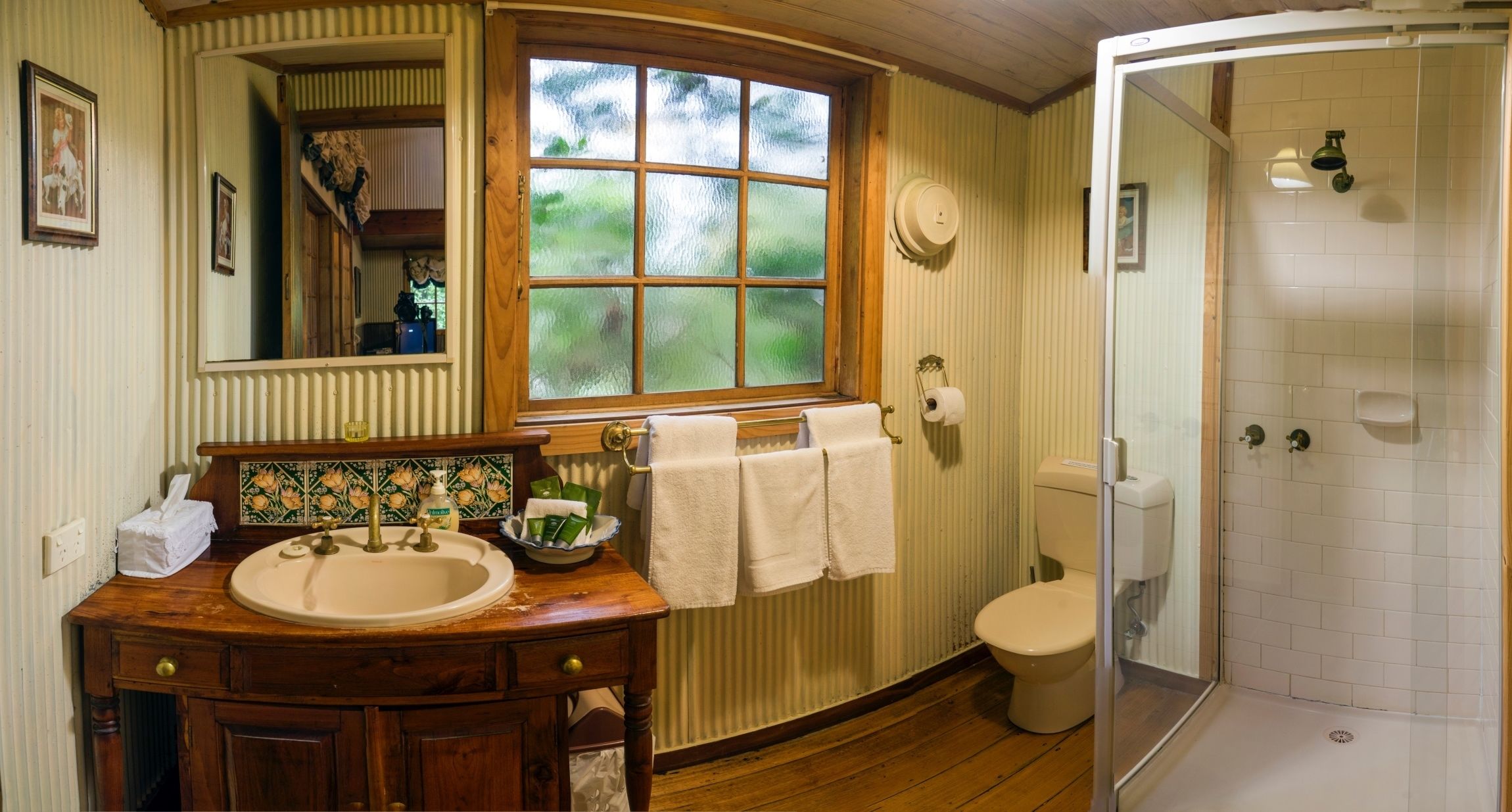 Une salle de bain avec un meuble-lavabo en bois, une fenêtre, des toilettes et une douche à parois de verre.