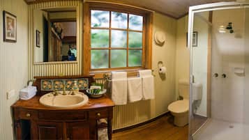 Une salle de bain avec un meuble-lavabo en bois, une fenêtre, des toilettes et une douche à parois de verre.