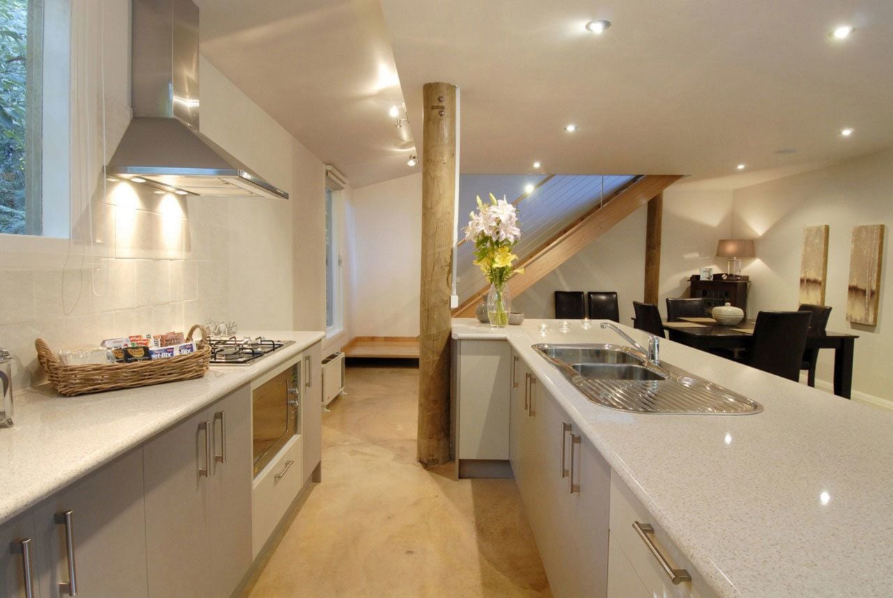 A modern kitchen with a central island, a built-in stove, and a large sink.