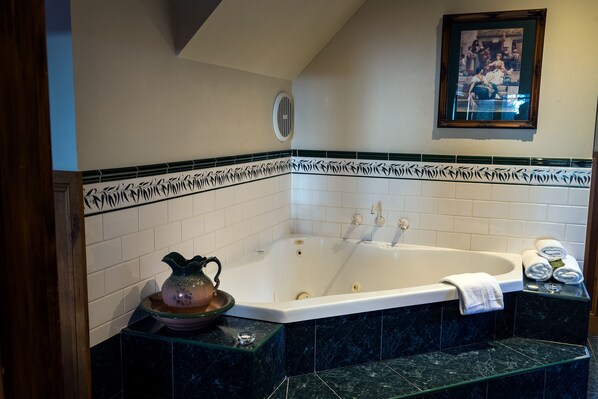 A bathroom with a freestanding bathtub, a decorative pitcher, and a framed picture on the wall. - Arnica Views (Mount Dandenong)