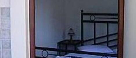 Una habitación con una cama individual, una mesita de noche pequeña y una silla.