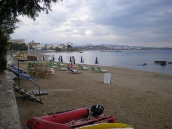 A beach with lounge chairs and umbrellas, a red vehicle, and a signboard.