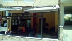 Un restaurant avec une terrasse, un menu affiché de manière visible et un panneau de signalisation en premier plan.