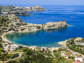 Un pueblo costero con una bahía rocosa, aguas azules cristalinas y edificios a lo largo de la costa.
