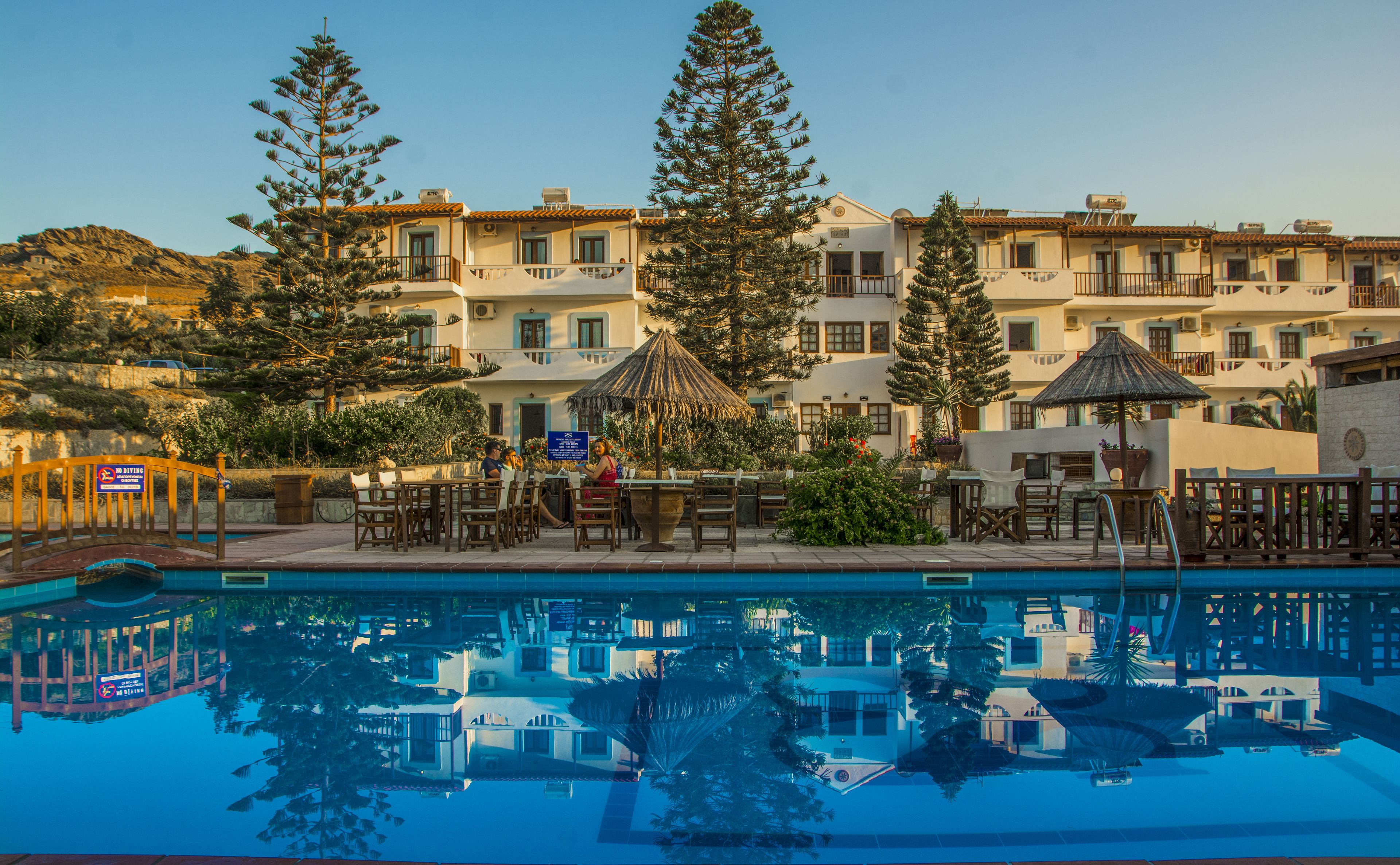 A hotel with a swimming pool, outdoor seating, and multiple buildings with balconies.