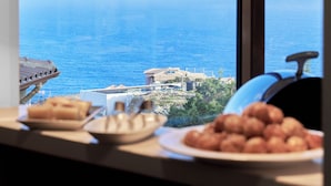 A kitchen with a view of the sea, two hanging copper pendant lights, and a plate of food on the counter. - Spiros-Soula Family Hotel & Apartments (Malevizi)