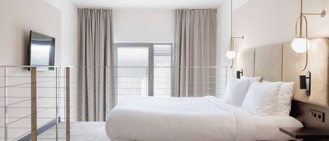 A modern bedroom with a large bed, a TV mounted on the wall, and a balcony with a railing.