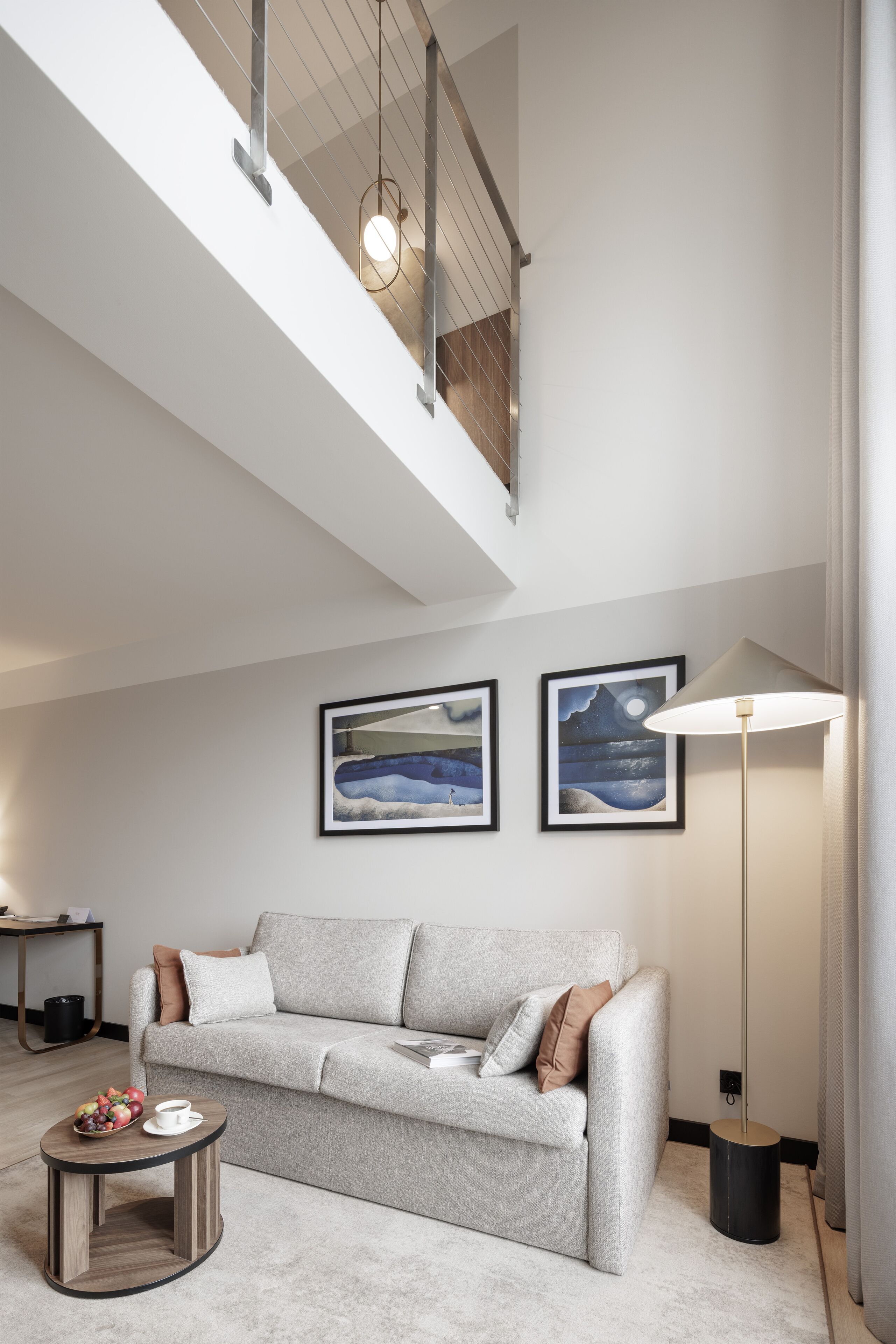 A modern living room with a grey sofa, a coffee table, and two framed artworks on the wall.