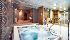 Un área de spa con bañera de hidromasaje, paredes con azulejos y detalles de madera.