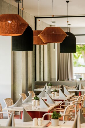 Un restaurante con mesas hexagonales, sillas de mimbre e iluminación colgante.