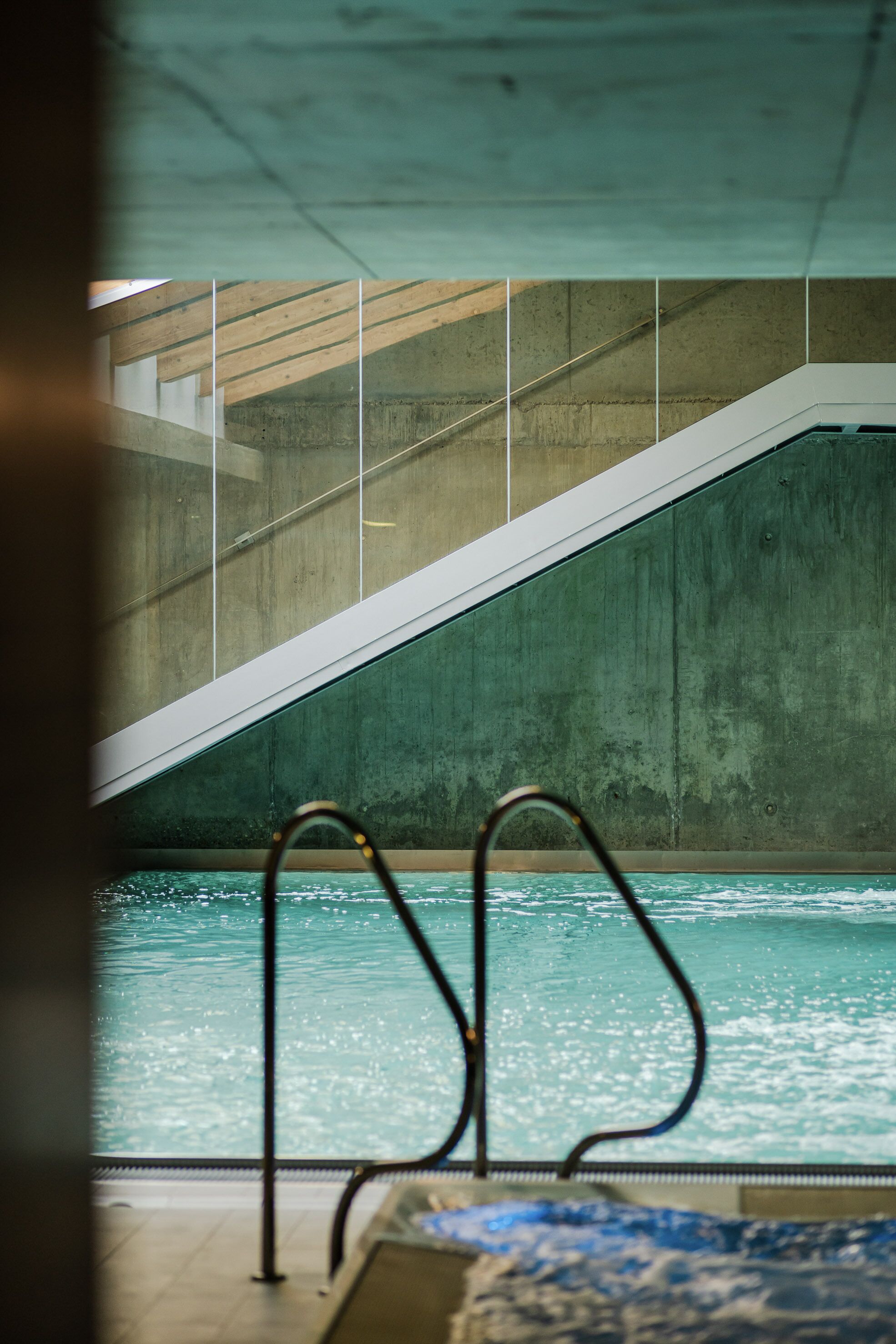 A swimming pool with a concrete wall and a metal staircase leading up to it.
