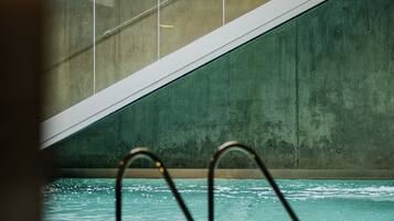 A swimming pool with a concrete wall and a metal staircase leading up to it.