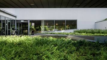 A modern building with a glass entrance, a bike rack, and a green rooftop garden.
