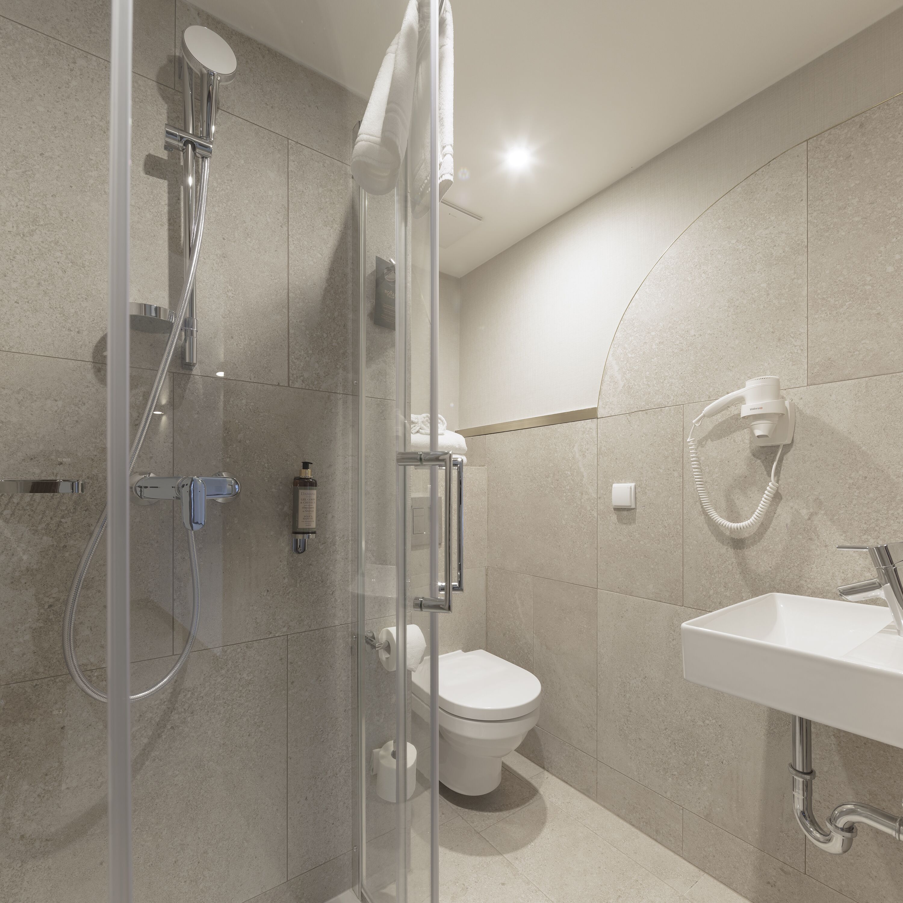 A modern bathroom with a glass-enclosed shower, a toilet, and a sink.