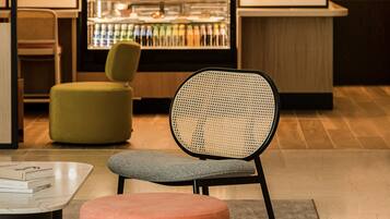A modern bar area with seating, a refrigerator stocked with beverages, and a warm ambient light.