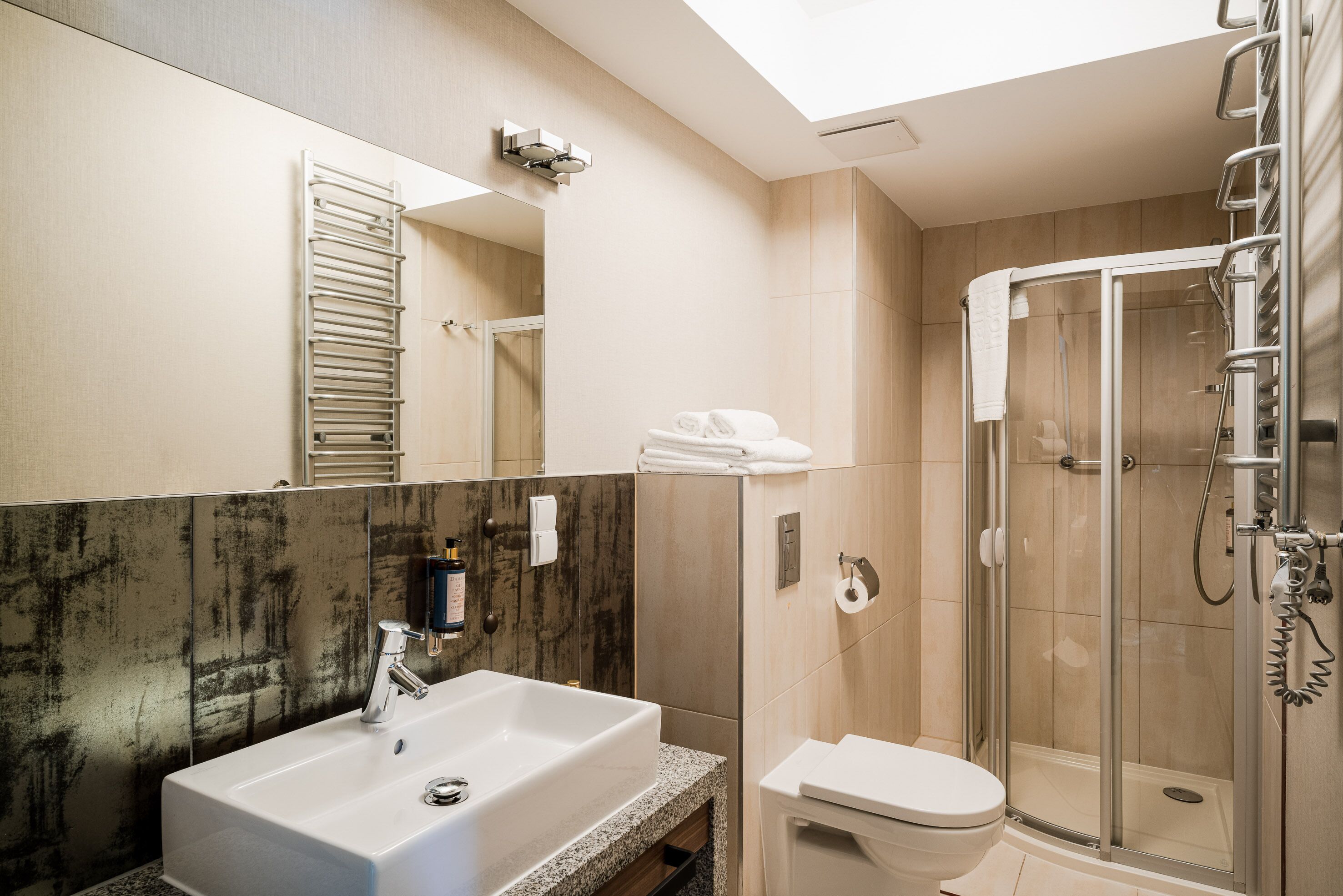 Une salle de bain moderne avec un grand miroir, un lavabo, des toilettes et une douche à parois de verre.