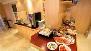 Zona de bufé con diferentes alimentos y un refrigerador.