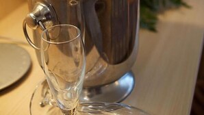 Una botella de champán en un balde de metal con una copa a su lado.