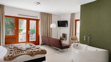 Een moderne slaapkamer met een groot bed, een bank, een televisie en een bad.