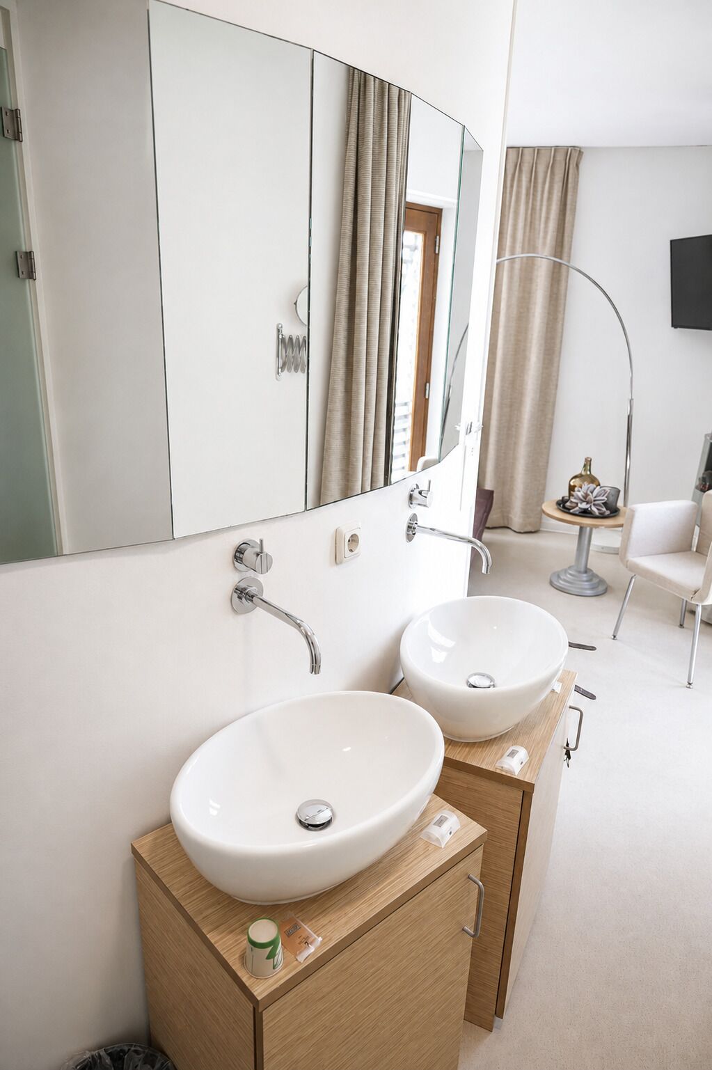 A modern bathroom with two white sinks, a large mirror, and a wooden vanity.