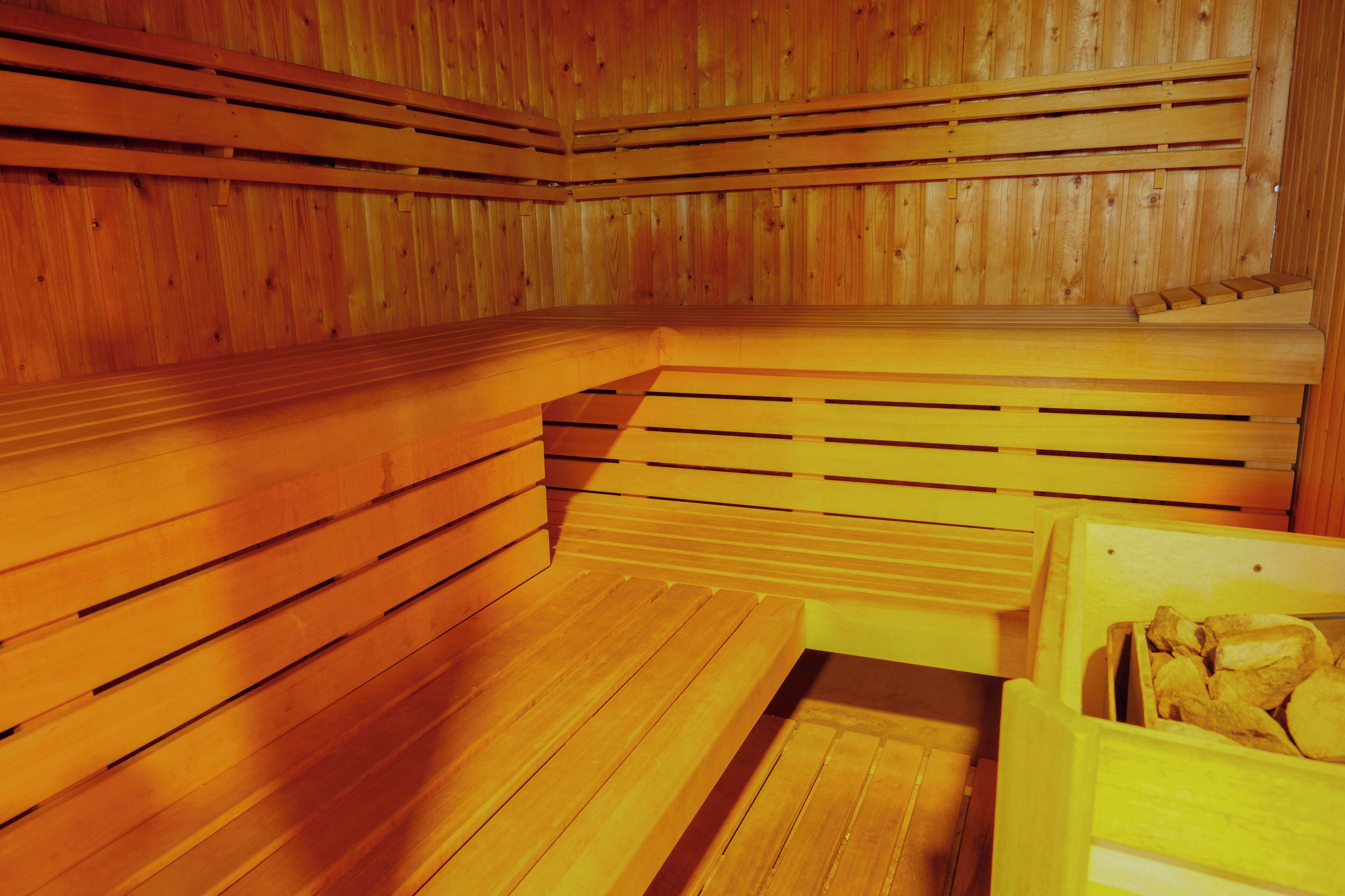 A sauna with wooden benches and a bench with a storage compartment containing logs.